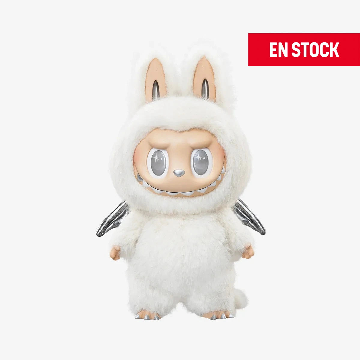 Figura coleccionable de Zimomo con temática de ángel, vestido con un traje esponjoso blanco de orejas largas y alas plateadas. El personaje tiene expresión seria y ojos plateados brillantes, con detalles suaves y acabados de alta calidad. En la esquina superior derecha aparece una etiqueta roja con el texto "EN STOCK"